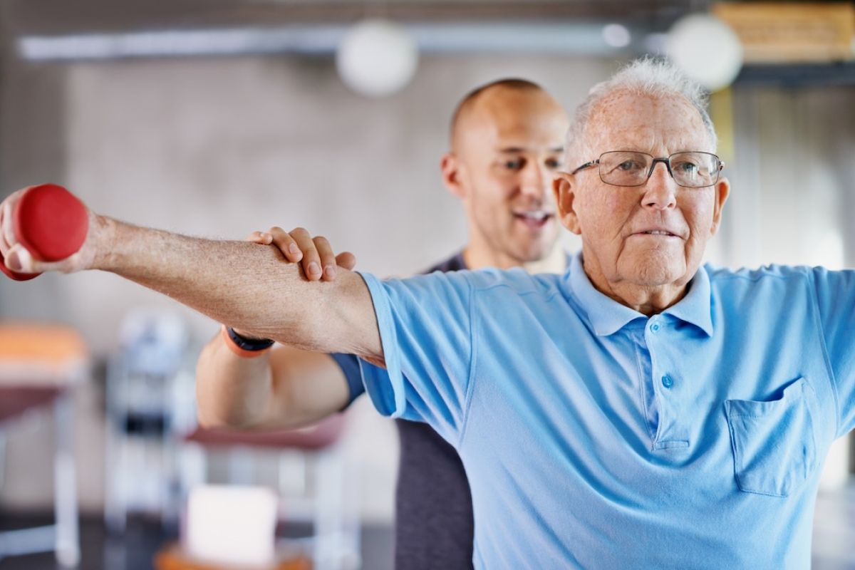 Shot of a physiotherapist helping a senior man with weights