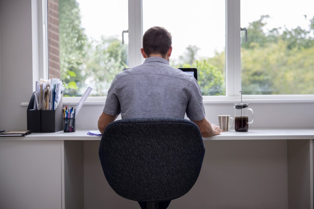 Man sitting with his back to the camera while he works on his laptop